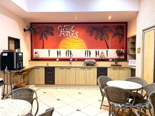a restaurant with tables and chairs and a large mural at Hotel Rosa da Ilha Guaruja - Perto do Mar com piscina in Guarujá