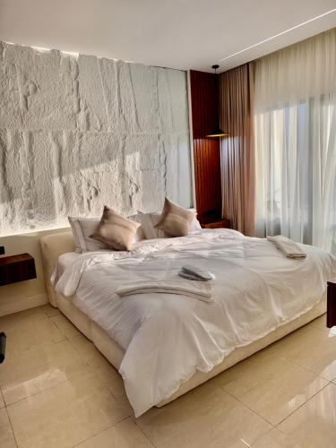 a large white bed in a bedroom with a stone wall at Damac Apartment شقة مع جاكوزي بإطلالة بحرية in Jeddah