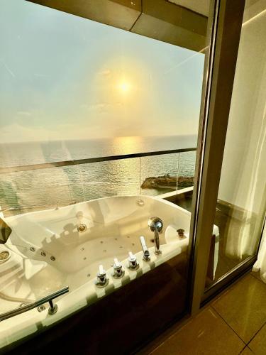 a bath tub in a bathroom with a view of the ocean at Damac Apartment شقة مع جاكوزي بإطلالة بحرية in Jeddah
