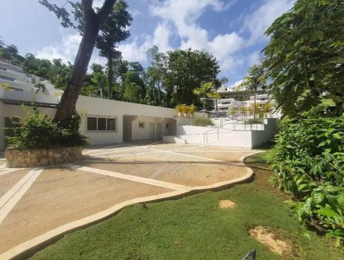 a white building with a tree in front of it at Suite with jacuzzi in Las Terrenas in El Limón