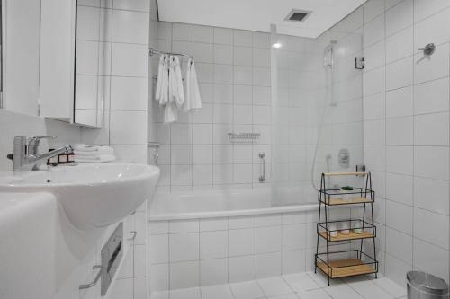 a white bathroom with a sink and a bath tub at Luxurious Apt Gym Tennis Carpark 6th Floor in Auckland