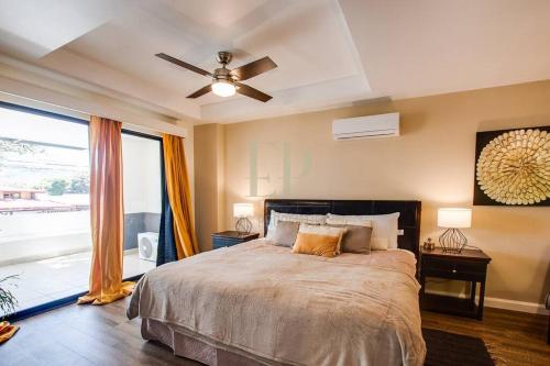 a bedroom with a bed with a ceiling fan and a window at CR MARIPOSA RENTALS Santa Ana Centro 2BR with Terrace Walk Everywhere in Santa Ana