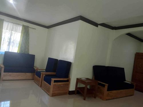 a room with blue chairs and a table and a window at Balai Mariacaria Pension House in Guindulman