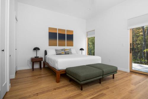 a bedroom with a white bed and a green ottoman at KOTI Vacation Rentals in Williamsburg