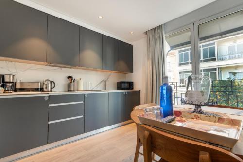 a kitchen with black cabinets and a table with a bottle at Apartamentos Turísticos La Plaza in Chipiona