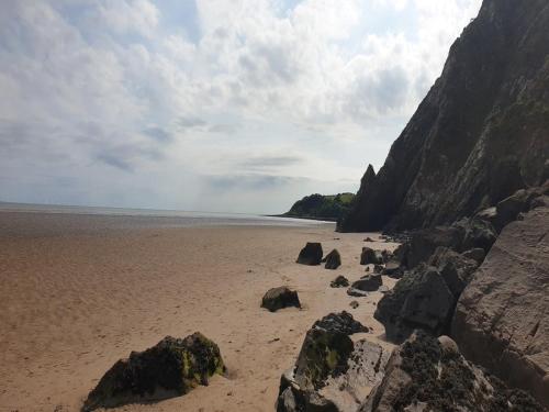 a beach with rocks on the sand and the ocean at 1 Bed in Sandyhills 85904 in Fairgirth