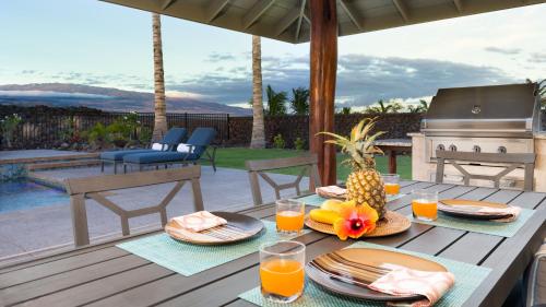 a wooden table with food and drinks on a patio at ❤PiH❤Aloha Paradise Large Private Pool Waterfall Spa PLUS 2024 Resort Pool Passes in Waikoloa