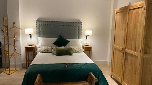 a bedroom with a large bed with green sheets and pillows at Apartamentos Turísticos La Plaza in Chipiona