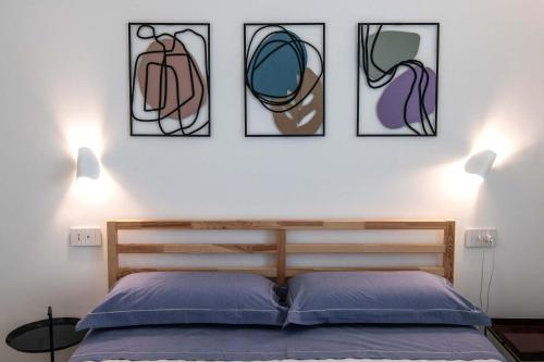 a bedroom with a bed with four pictures on the wall at Appartamenti Aurelia 89 in Nardò