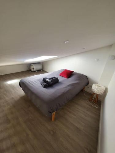 une chambre avec un grand lit avec un oreiller rouge dans l'établissement Superbe appartement rénové - Lyon-Groupama stadium, à Rillieux-la-Pape