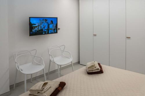a room with two white chairs and a tv on the wall at Appartamenti Aurelia 89 in Nardò