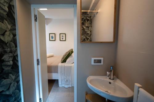 a bathroom with a sink and a mirror and a bed at Uniconico Trullo & Rooms in Alberobello