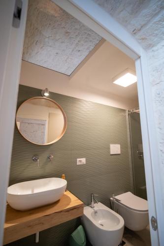 a bathroom with a sink and a mirror and a toilet at Uniconico Trullo & Rooms in Alberobello