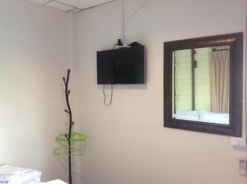 a room with a mirror and a tv on the wall at NTY Hostel Near Suvarnabhumi Airport in Bangkok