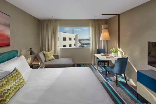 a hotel room with a large bed and a table at Crown Promenade Perth in Perth