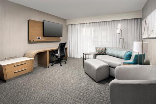 a hotel room with a desk and a couch at Courtyard by Marriott Portland Hillsboro in Hillsboro