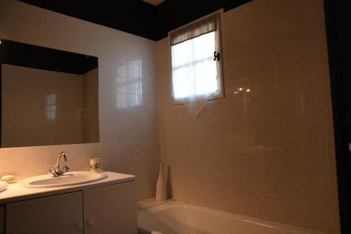 La salle de bains est pourvue d'un lavabo, d'une baignoire et d'une fenêtre. dans l'établissement Les Restanques Charmante petite maison nature et calme Grasse, à Grasse