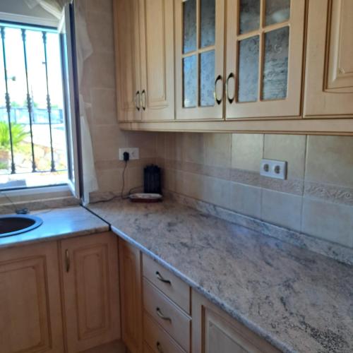 a kitchen with wooden cabinets and a sink and a window at Chamarin in Arboleas
