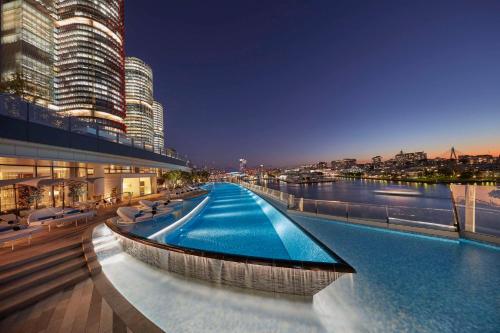 a large building with a large swimming pool next to a river at Crown Towers Sydney in Sydney