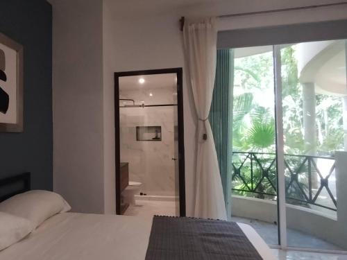 a bedroom with a bed and a bathroom with a balcony at Secret Waters 104 in Puerto Aventuras