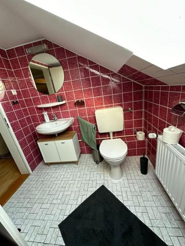 a red tiled bathroom with a toilet and a sink at Ferienwohnung im Deister in Springe