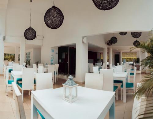 a dining room with white tables and white chairs at Dharma Hotel Boutique Spa in San Jerónimo