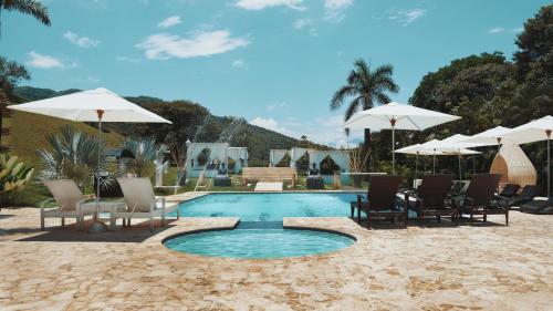 a swimming pool with chairs and umbrellas on a beach at Dharma Hotel Boutique Spa in San Jerónimo