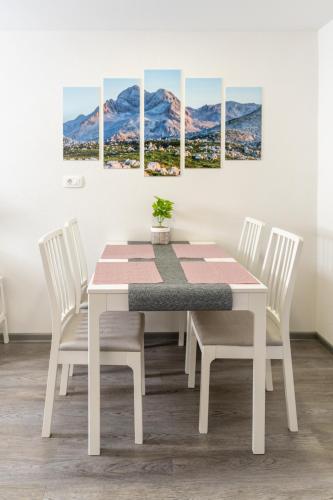 a white dining room table with four chairs and a painting at Apartma pri lipi in Bohinj