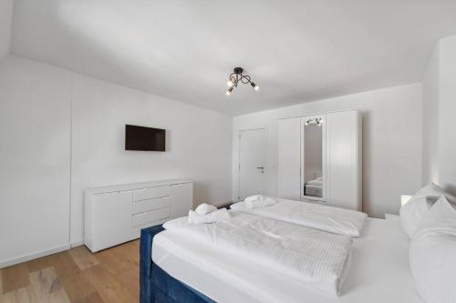 a white bedroom with two beds and a mirror at Infinity Stay Ferienapartments Rheinstrasse in Wilhelmshaven