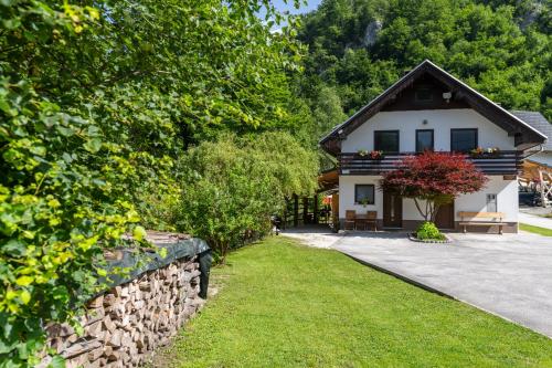 a house with a stone wall next to a yard at Apartma pri lipi in Bohinj