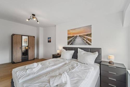 a bedroom with a large bed with a painting on the wall at Infinity Stay Ferienapartments Rheinstrasse in Wilhelmshaven