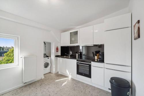 a white kitchen with white cabinets and a window at Infinity Stay Ferienapartments Rheinstrasse in Wilhelmshaven
