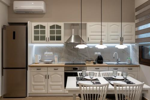 a kitchen with white cabinets and a table with chairs at "Meteora Magic" apartments in Kalabaka