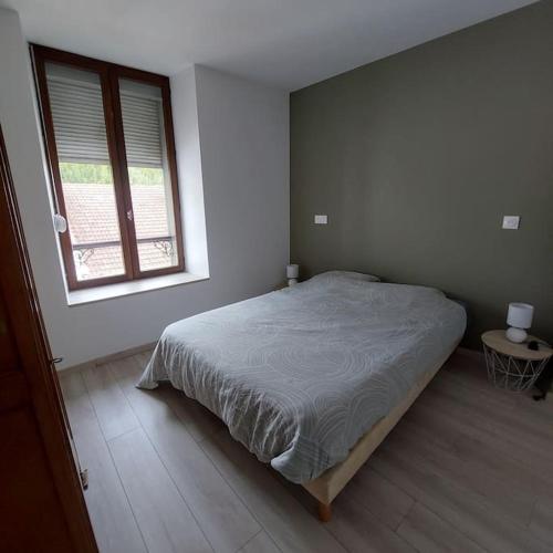 une chambre avec un grand lit et une fenêtre dans l'établissement appartement rénové centre ville, à Bourbonne-les-Bains