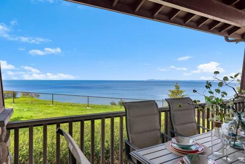 a table and chairs on a balcony with a view of the ocean at Puget Sound Sunset - Whidbey Ocean Front home with C in Oak Harbor