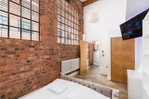 an exposed brick wall in a room with a television at High End Luxury Townhouse in JQ, 4 Bedrooms, Flat screen TV in all rooms, Free Parking, Near Birmingham City Centre DEPOSIT REQUIRED in Birmingham