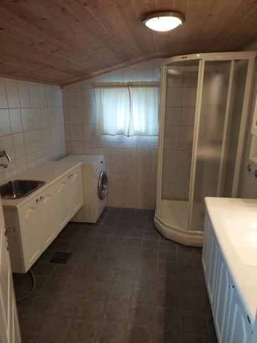 a bathroom with a shower and a washing machine at Jovollstua i Eresfjord med båt til leie in Øverås