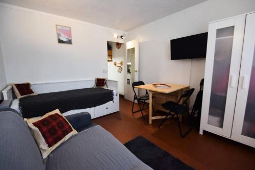 Cette chambre comprend un lit et une table avec un bureau. dans l'établissement Résidence Le Sierra Nevada - Studio 2/3 personnes - LE SIERRA NEVADA -PLAGNE CENTRE MAE-4531, à La Plagne Tarentaise