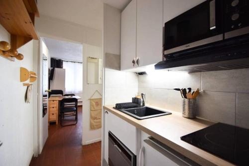 une petite cuisine avec un évier et un micro-ondes dans l'établissement Résidence Le Sierra Nevada - Studio 2/3 personnes - LE SIERRA NEVADA -PLAGNE CENTRE MAE-4531, à La Plagne Tarentaise