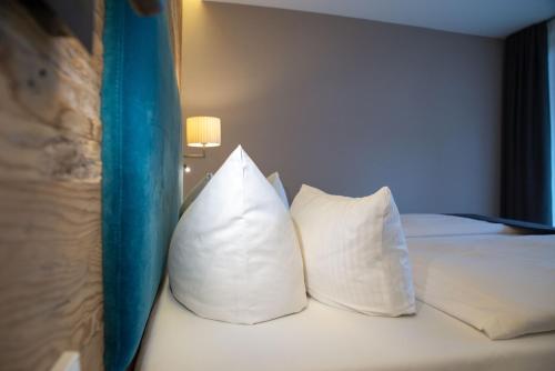 a bed with white pillows on it in a room at Das.Hochgrat in Oberstaufen
