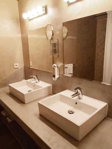 une salle de bain avec deux lavabos et un grand miroir dans l'établissement Des Lits Sur La Place, à Hérépian