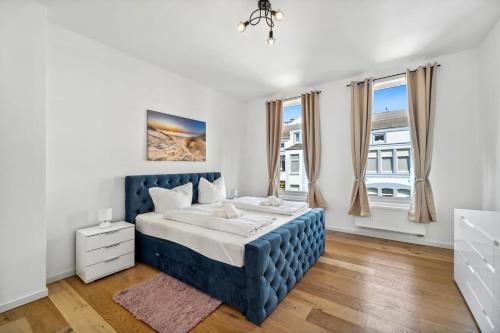 a bedroom with a blue bed and windows at Infinity Stay Ferienapartments Rheinstrasse in Wilhelmshaven