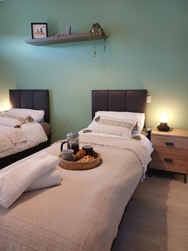 a bedroom with two beds with a tray of food on the bed at Sunlit garden bungalow in Puriton