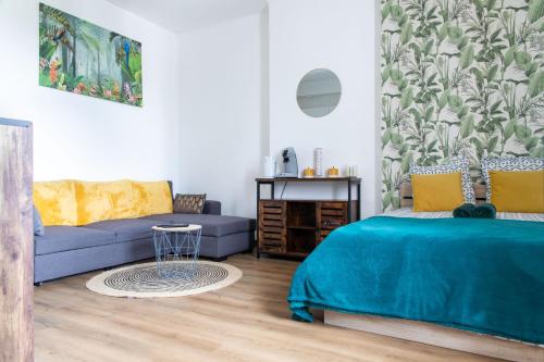 - une chambre avec un lit bleu et un canapé dans l'établissement Studio Lorient Proche Centre Gare Wifi Netflix, à Lorient