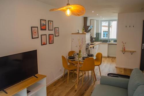 a living room with a table and chairs and a kitchen at L'Escapade Médiévale Appartement neuf in Josselin