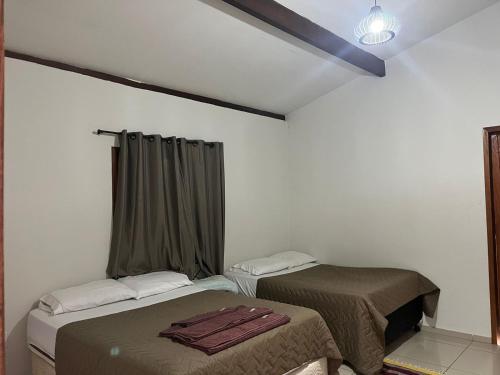 a room with two beds and a window with curtains at Casa da Arvore in Mariana