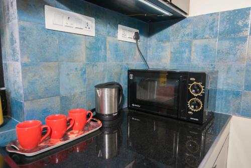 a kitchen with red cups on a tray next to a microwave at 'Golden Sea Pearl' 1 bhk Beach apartment in Benaulim