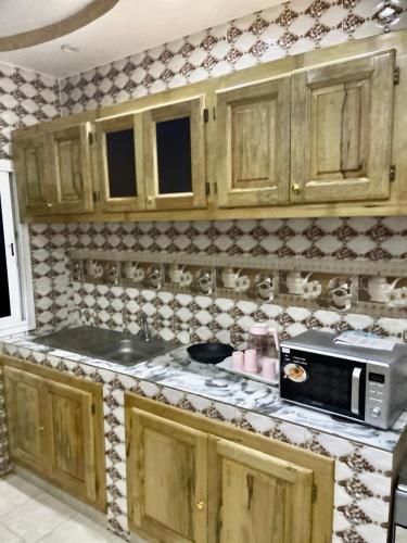 a kitchen with wooden cabinets and a microwave at Appartement meublés in Dakar