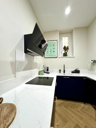 Il comprend une cuisine avec des comptoirs blancs et une télévision murale. dans l'établissement Appartement de luxe à deux pas des Halles, quai Valliere, à Narbonne