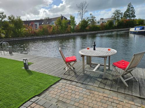 a table with two chairs and a bottle on it next to the water at Lemmer House - Luxe familiehuis aan het water in Lemmer